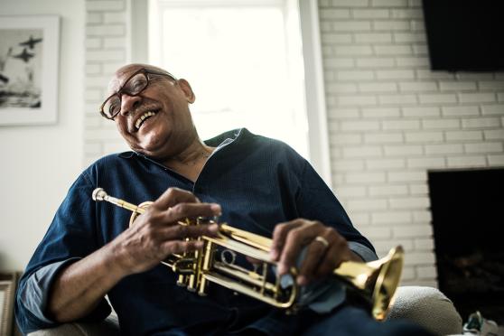 A smiling man holding a trumpet
